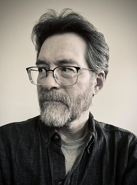 Black and white photo of Kent Lew from the shoulders up, looking off to his right.